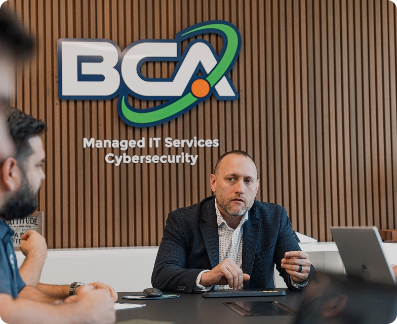 Business professionals meet at BCA's office to discuss cybersecurity strategies and Managed Compliance as a Service under the company’s branding.
