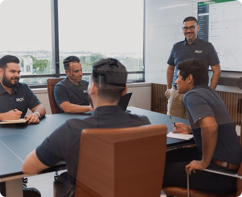 The BCA team collaborates in a conference room, reviewing cybersecurity tools and strategies focused on delivering Managed Compliance as a Service to clients.
