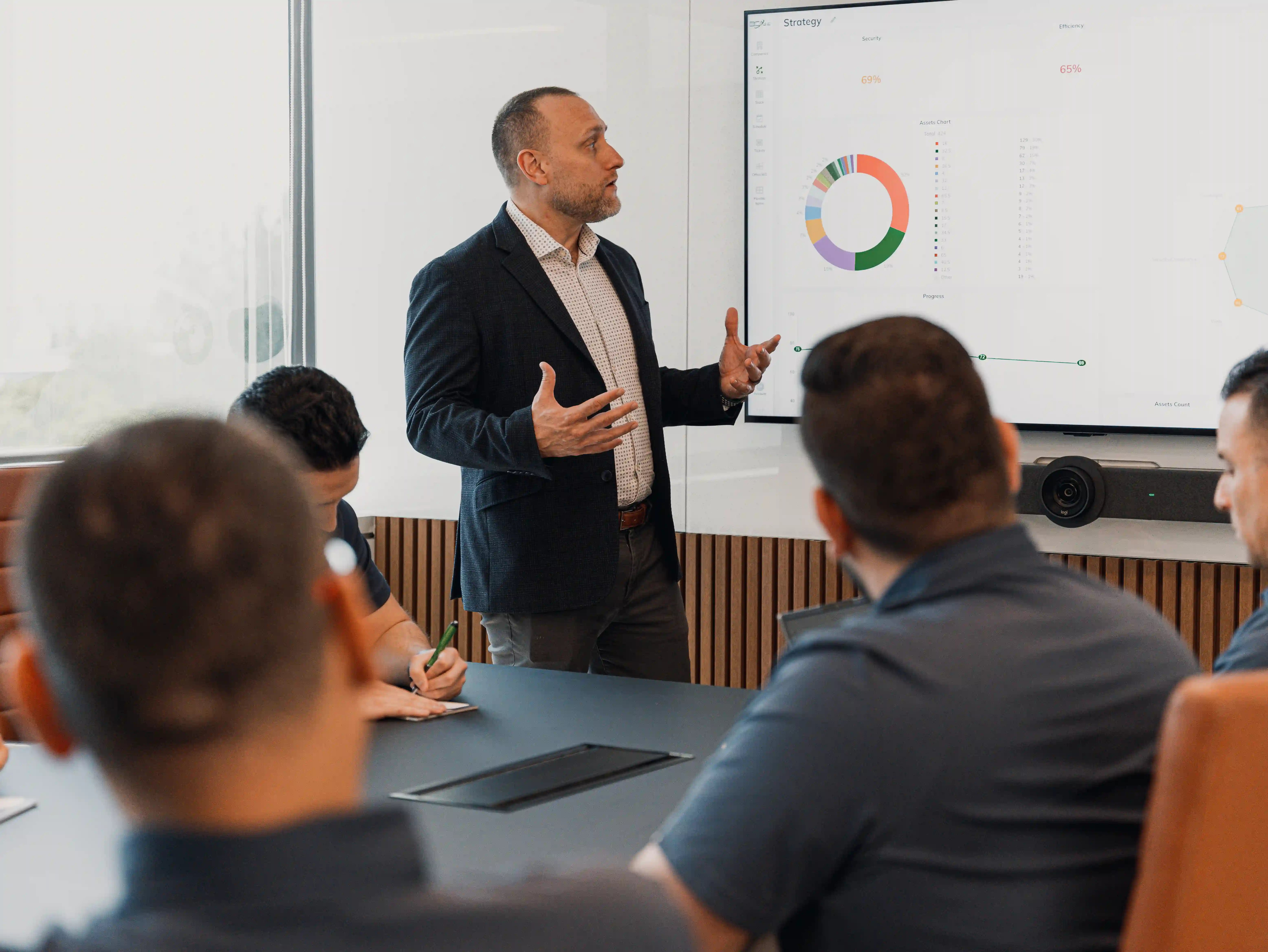 A business leader presents a strategy dashboard to the BCA team, highlighting performance metrics and the impact of scalable, secure cloud services on business efficiency.