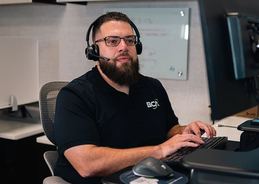 BCA IT help desk engineer working at a computer workstation.