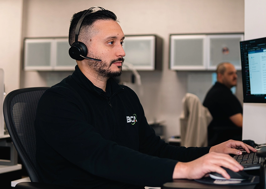BCA IT help desk technician assisting a client from a computer workstation.