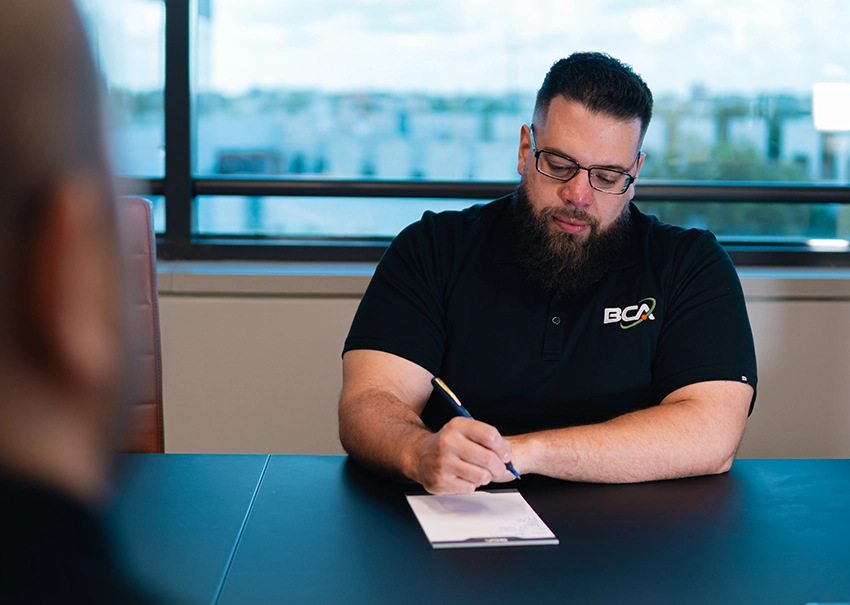 BCA IT consultant documenting business needs during a meeting.