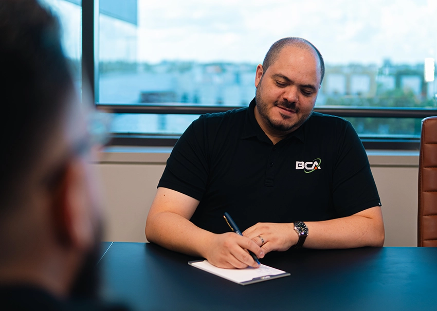 BCA IT consultant listening and taking notes during a meeting.