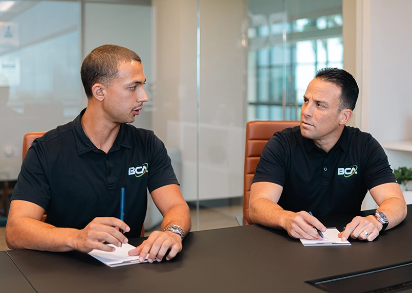 Two BCA IT team members discussing technology strategy at a conference table.