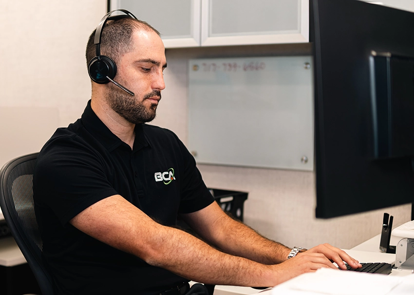 BCA IT technician providing remote support from a help desk workstation.