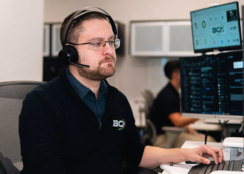 BCA IT support specialist assisting clients from a help desk workstation.