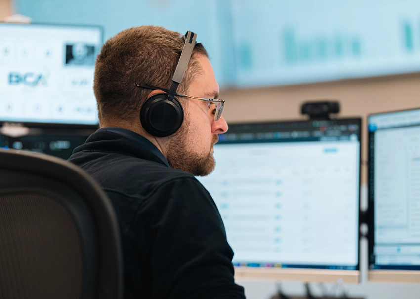 BCA IT technician monitoring client systems from multiple screens.