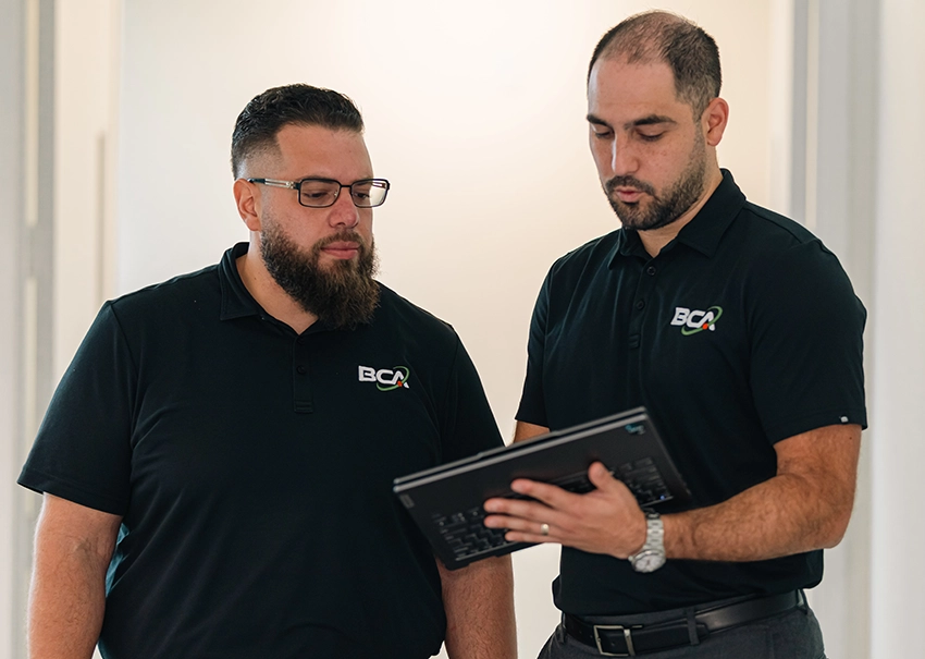 Two BCA IT team members reviewing project information on a tablet.