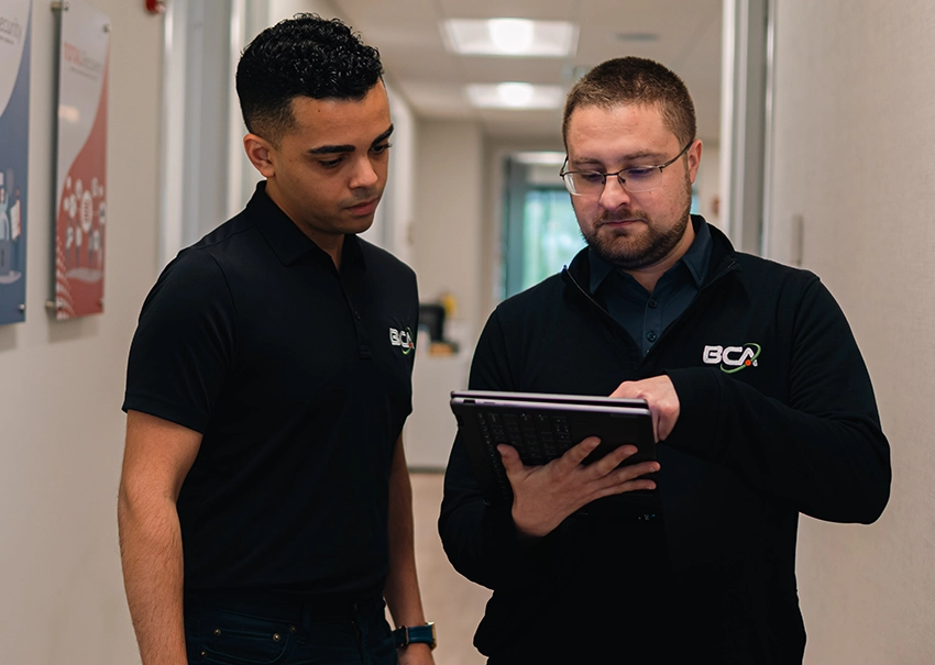 Two BCA IT technicians reviewing a work order on a tablet.