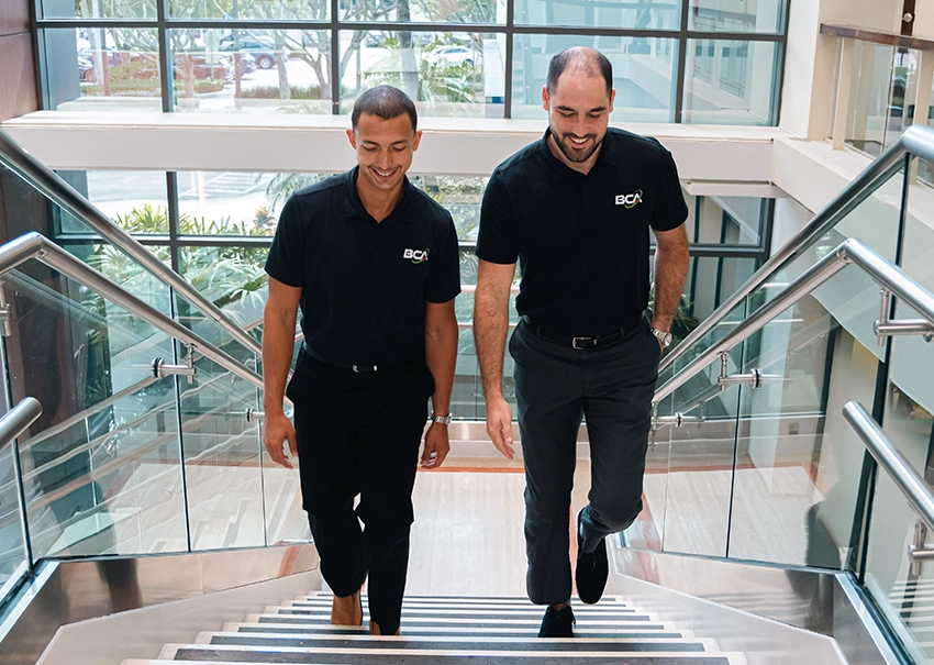 Two BCA IT team members walking up the office stairs.