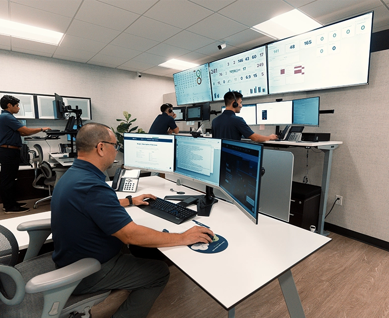 BCA team members monitor multiple screens in a network operations center, providing real-time IT support and cybersecurity management.