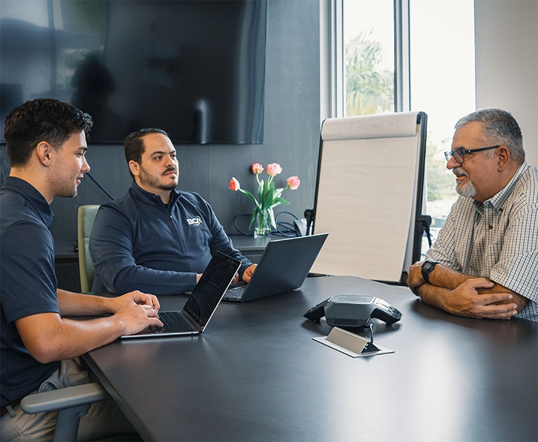 BCA team members providing IT consulting to a client in a conference room, with laptops open and a collaborative atmosphere.