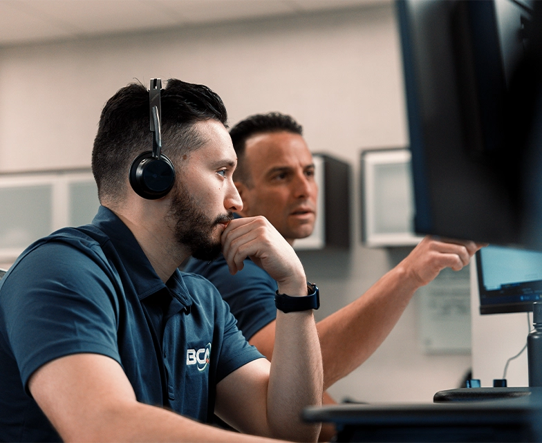 A focused IT support technician at BCA works at his desk with a headset on, engaging with clients via a digital help desk platform.